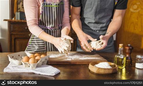 mid section couple preparing dough with baking ingredients wooden table