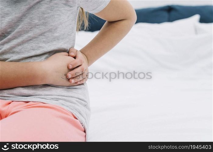 mid section girl touching her wrist with hands sitting bed. High resolution photo. mid section girl touching her wrist with hands sitting bed. High quality photo