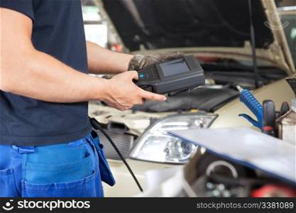 Mid section of mechanic holding a diagnostic tool