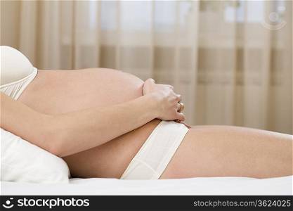 Mid section of pregnant woman in bra and panties