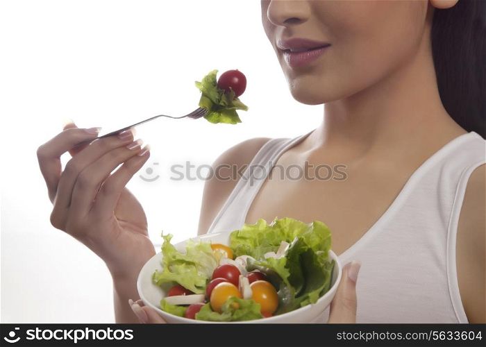 Mid section of woman eating salad of lettuce, cherry tomatoes and mushrooms isolated over white background