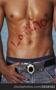 Mid section view of a bare chested young man with Latino written on his chest