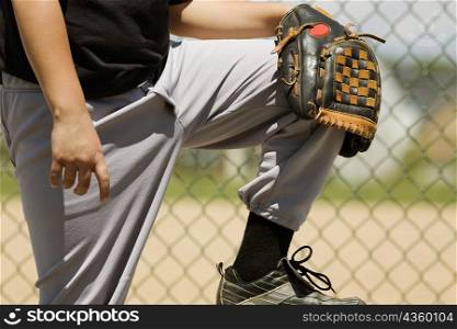 Mid section view of a baseball player holding a baseball glove