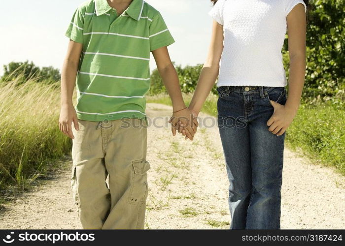 Mid section view of a boy and a girl standing holding hands