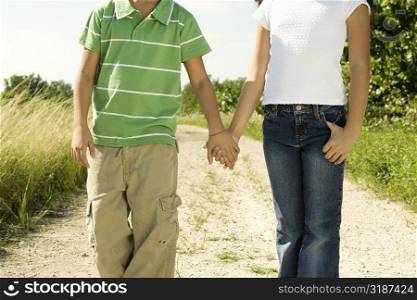 Mid section view of a boy and a girl standing holding hands