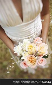 Mid section view of a bride holding a bouquet of flowers