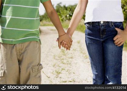 Mid section view of a brother and sister holding hands
