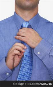 Mid section view of a businessman adjusting his tie