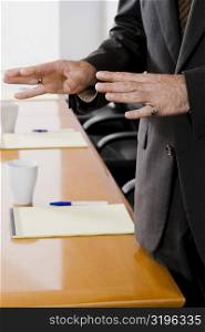 Mid section view of a businessman gesturing in a conference room