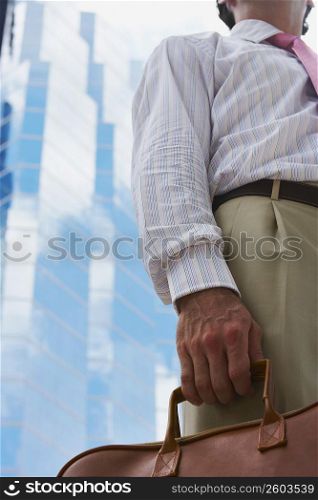 Mid section view of a businessman holding a handbag