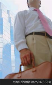 Mid section view of a businessman holding a handbag