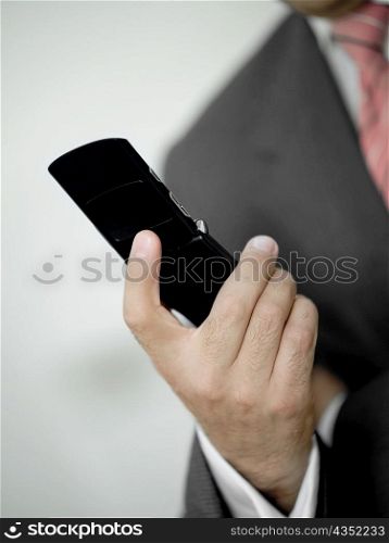 Mid section view of a businessman holding a mobile phone