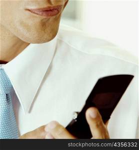 Mid section view of a businessman holding a mobile phone
