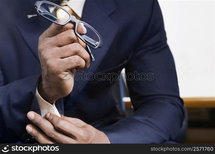 Mid section view of a businessman holding eyeglasses