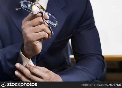Mid section view of a businessman holding eyeglasses