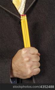 Mid section view of a businessman holding three pencils