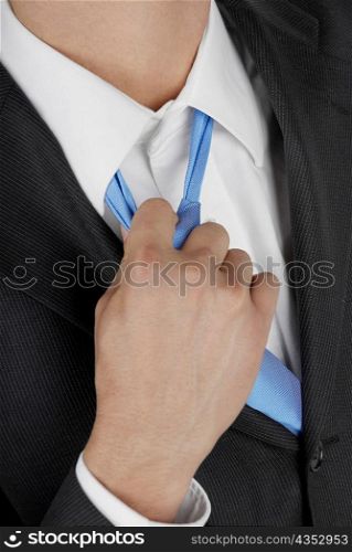 Mid section view of a businessman pulling his tie