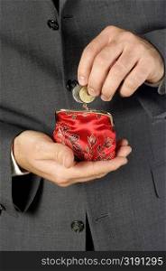 Mid section view of a businessman putting money into a change purse