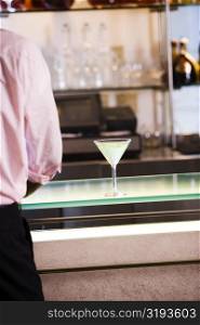 Mid section view of a businessman standing at a bar counter