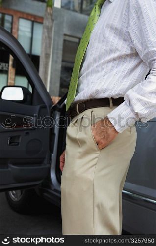 Mid section view of a businessman standing near a car