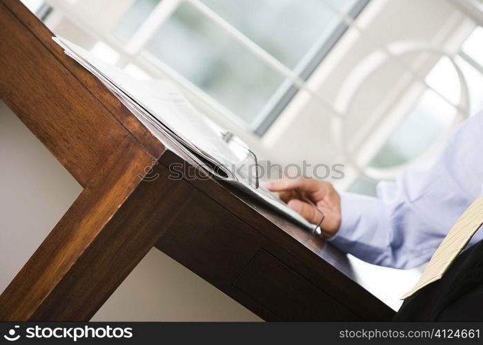 Mid section view of a businessman standing near a table