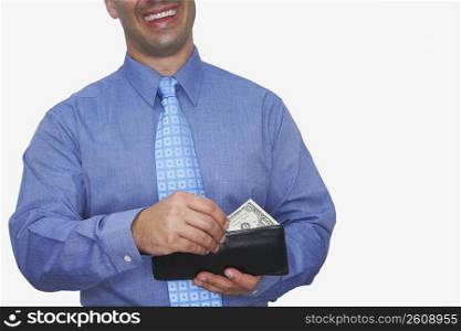 Mid section view of a businessman taking one dollar bill out of his wallet and smiling