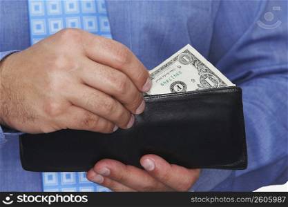 Mid section view of a businessman taking one dollar bill out of his wallet