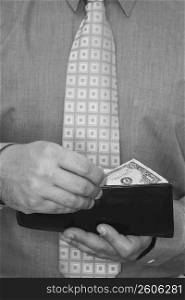 Mid section view of a businessman taking one dollar bill out of his wallet