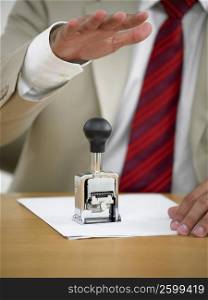 Mid section view of a businessman using a stamp