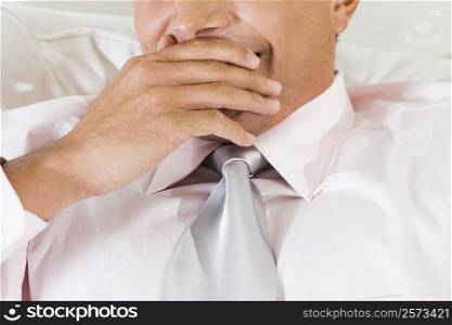 Mid section view of a businessman yawning