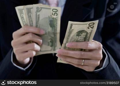 Mid section view of a businesswoman counting American paper currency