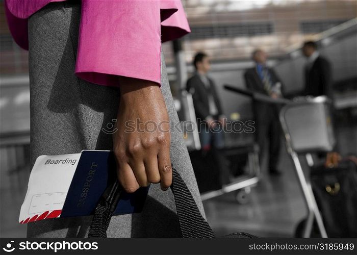 Mid section view of a businesswoman holding a passport with an airplane ticket