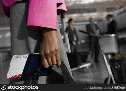 Mid section view of a businesswoman holding a passport with an airplane ticket