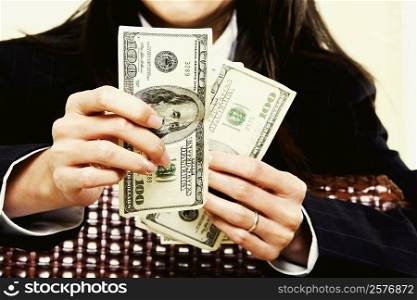 Mid section view of a businesswoman holding dollar bills
