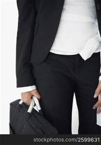 Mid section view of a businesswoman standing and holding a bag