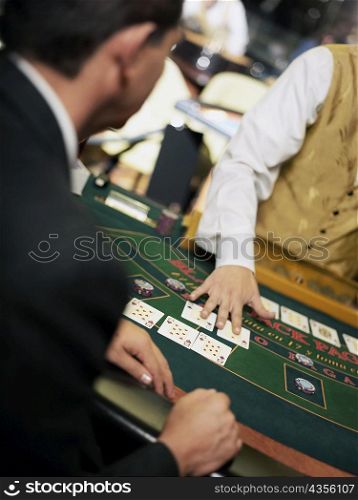 Mid section view of a casino worker dealing with playing cards on a gambling table