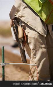 Mid section view of a construction worker carrying hand tools