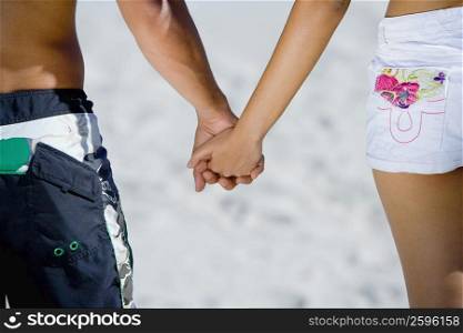 Mid section view of a couple holding hands