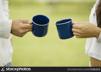 Mid section view of a couple holding two cups