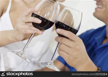 Mid section view of a couple toasting with wine glasses