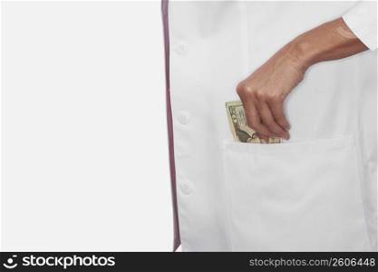 Mid section view of a female doctor taking out twenty dollar bill from her pocket