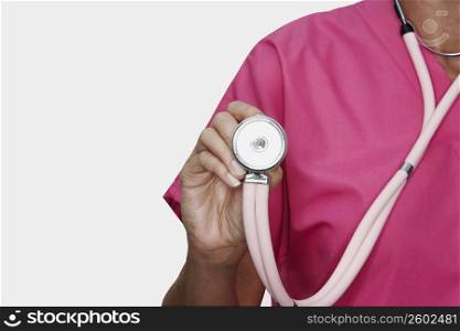 Mid section view of a female nurse holding a stethoscope