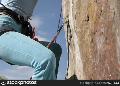 Mid section view of a female rock climber climbing a rock face