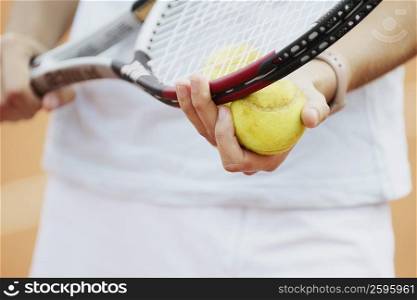 Mid section view of a female tennis player holding a tennis racket and a tennis ball