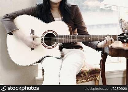 Mid section view of a girl playing the guitar