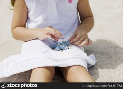 Mid section view of a girl playing with a starfish