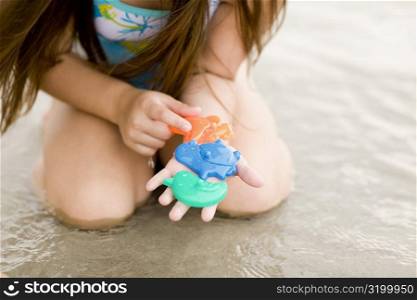 Mid section view of a girl playing with toys on the beach