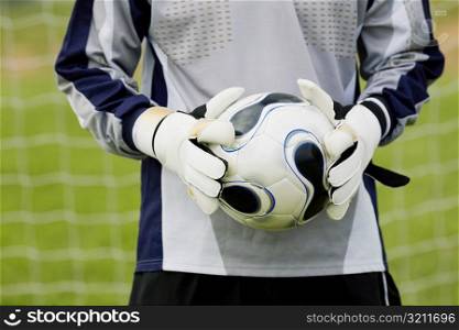 Mid section view of a goalie holding a soccer ball