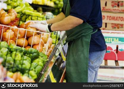 Mid section view of a grocer standing in a supermarket