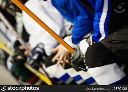 Mid section view of a group of ice hockey players holding ice hockey sticks